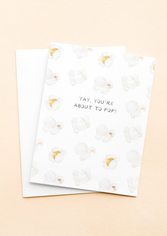 A greeting card with illustrated popcorn print and text at center reading "Yay, You're About To Pop!"